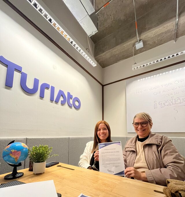 Clienta de Turisto Colombia recibiendo su comprobante de pago en la oficina